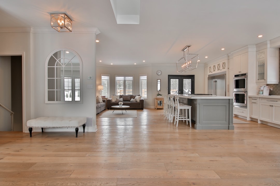 The bright, minimalist interior of a custom-built home featuring floor-to-ceiling windows that offer an unobstructed view of the outdoors, highlighting unique architectural design.
