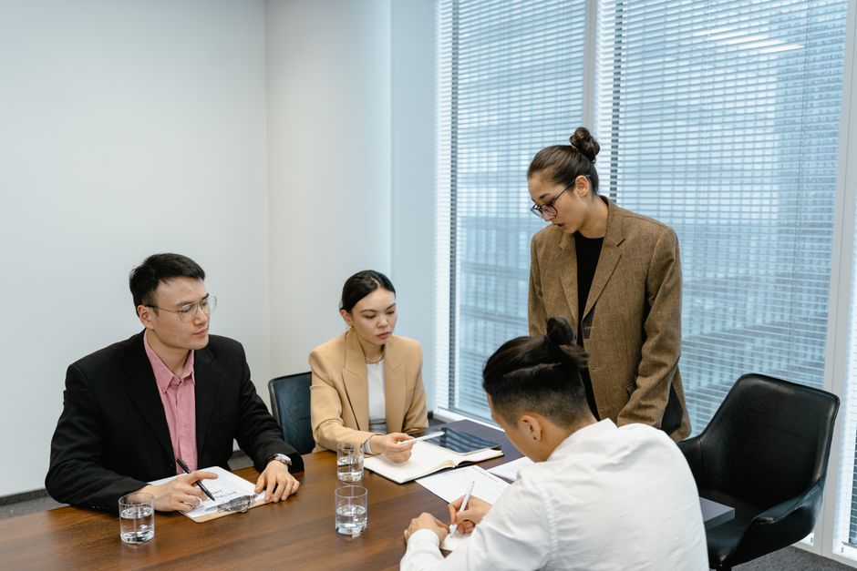 A diverse team of professionals collaborates around a table in a sunlit meeting room, symbolizing the network of services every Keswick real estate agent needs.