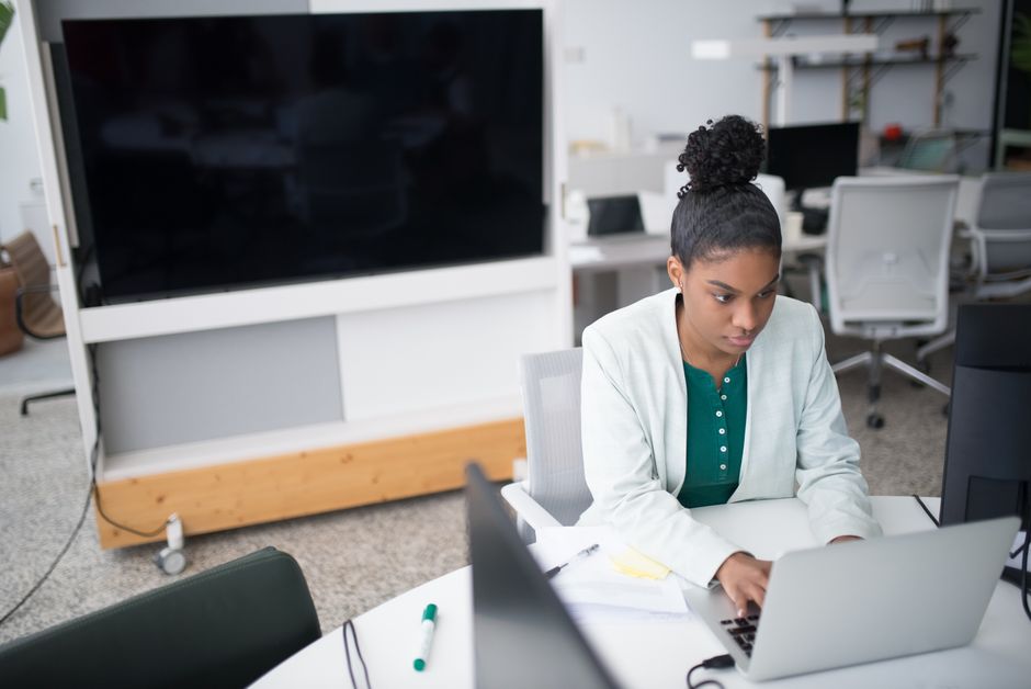 Professional and successful real estate agent works diligently on a laptop in a bright, modern office space, representing ...