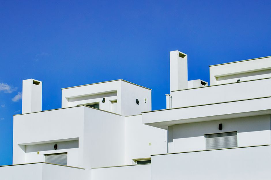 The clean, bright exterior of a modern minimalist house under a clear sky, representing a successful, forward-thinking real estate business in the AI era.